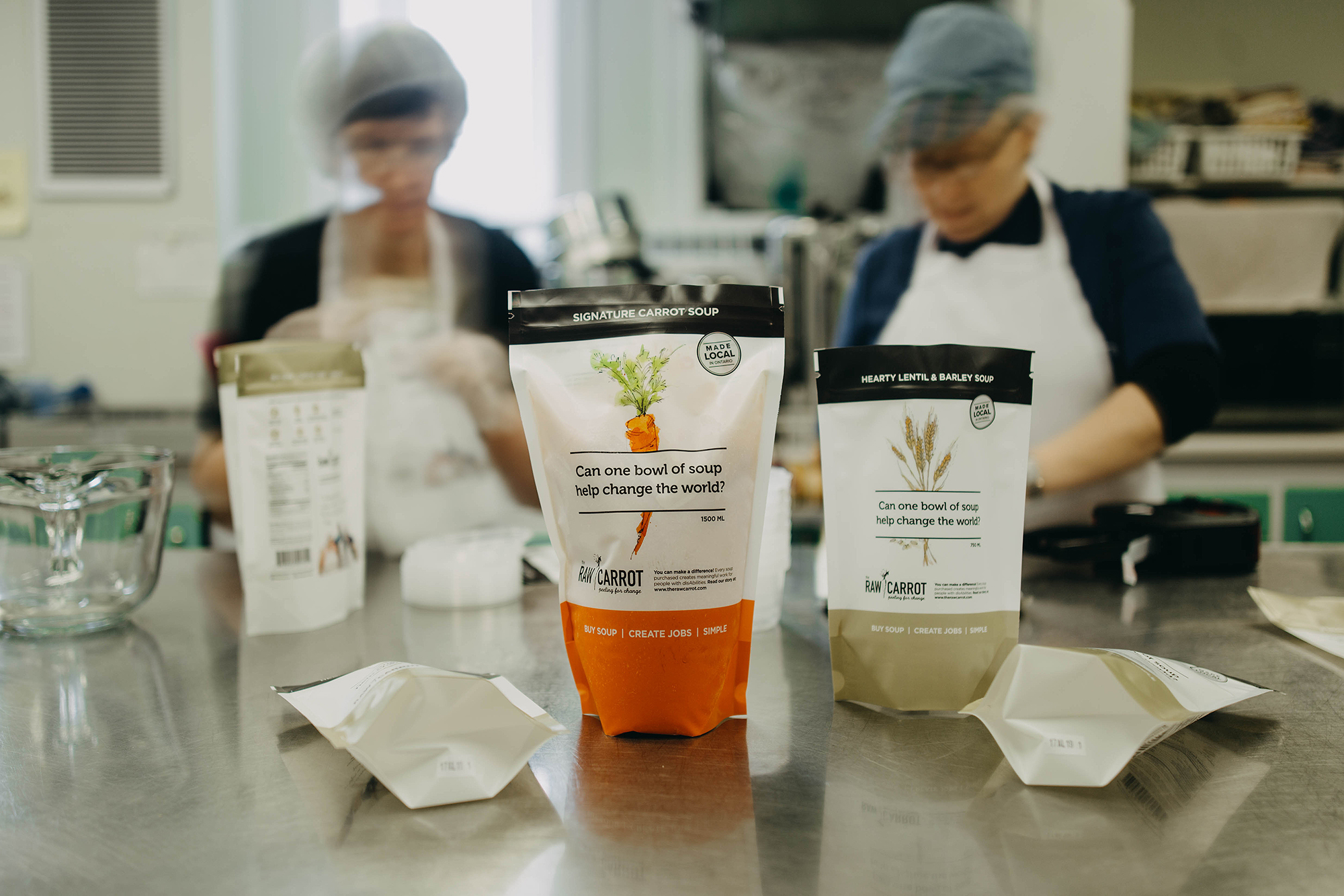 Raw carrot packages with employees blurred in the background.