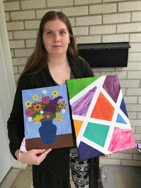 A Raw Carrot staff member holds her art for show
